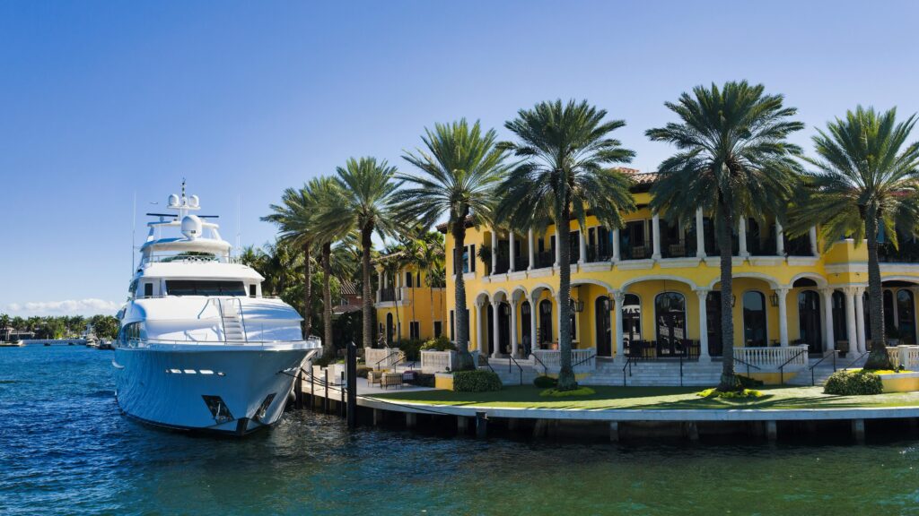 A stunning view of a luxury yacht docked beside a grand mansion in Fort Lauderdale, Florida.
